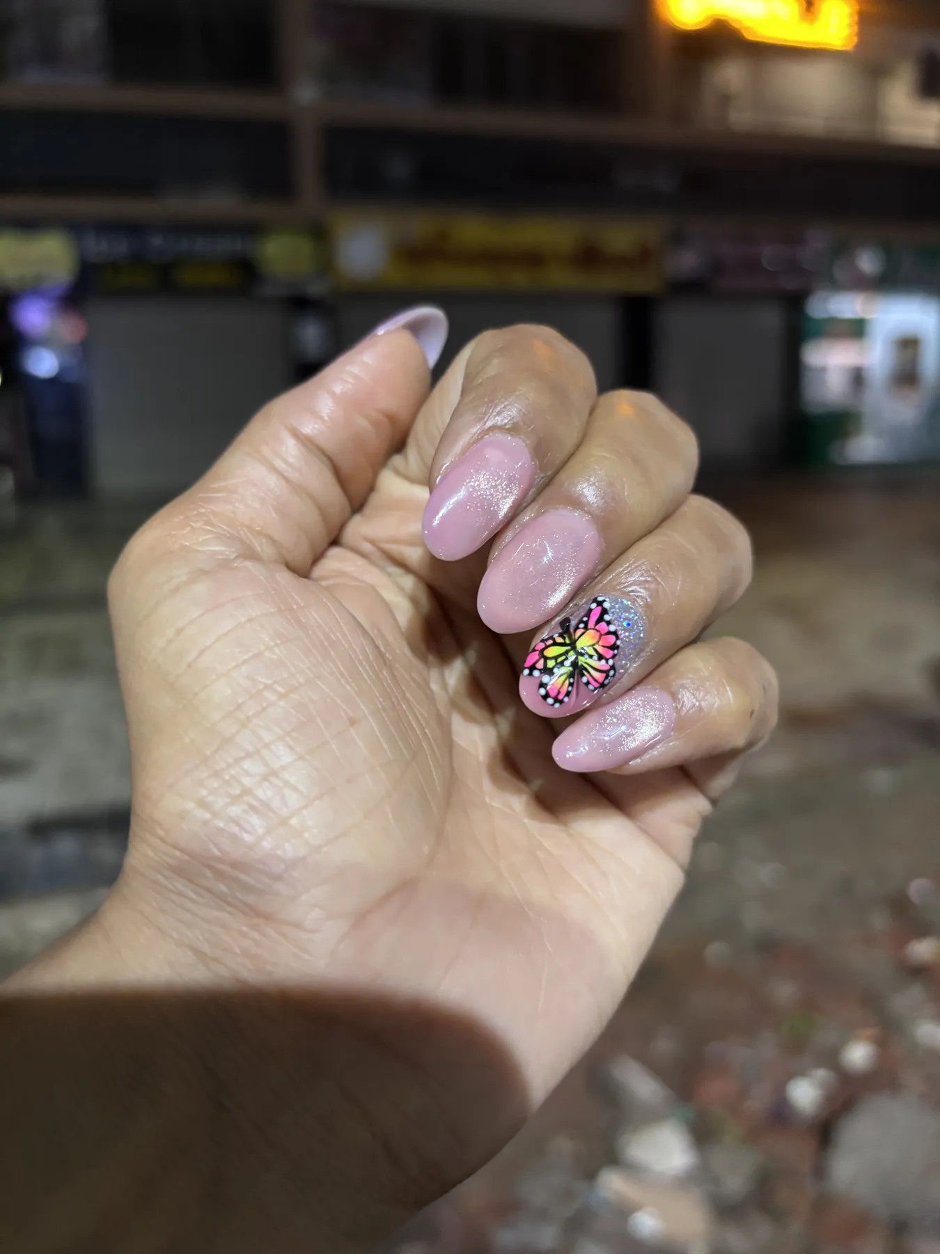 Pink almond nails with butterfly accent nail art Ahmedabad